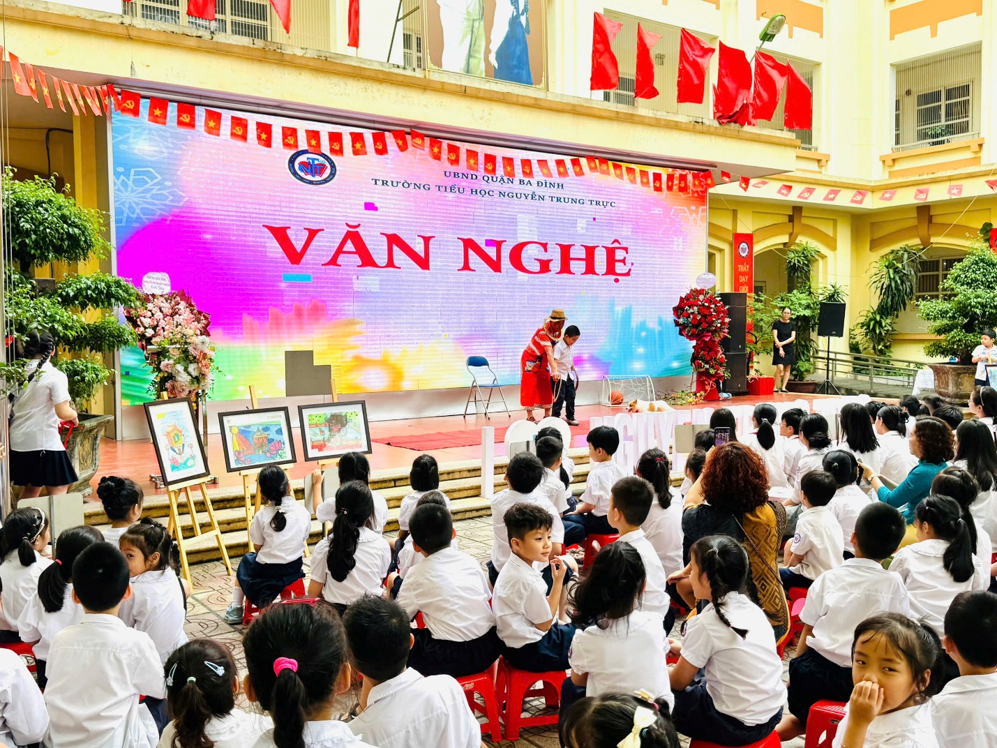 A group of children sitting on chairs in front of a large screen with Fengjia Night Market in the background

AI-generated content may be incorrect.