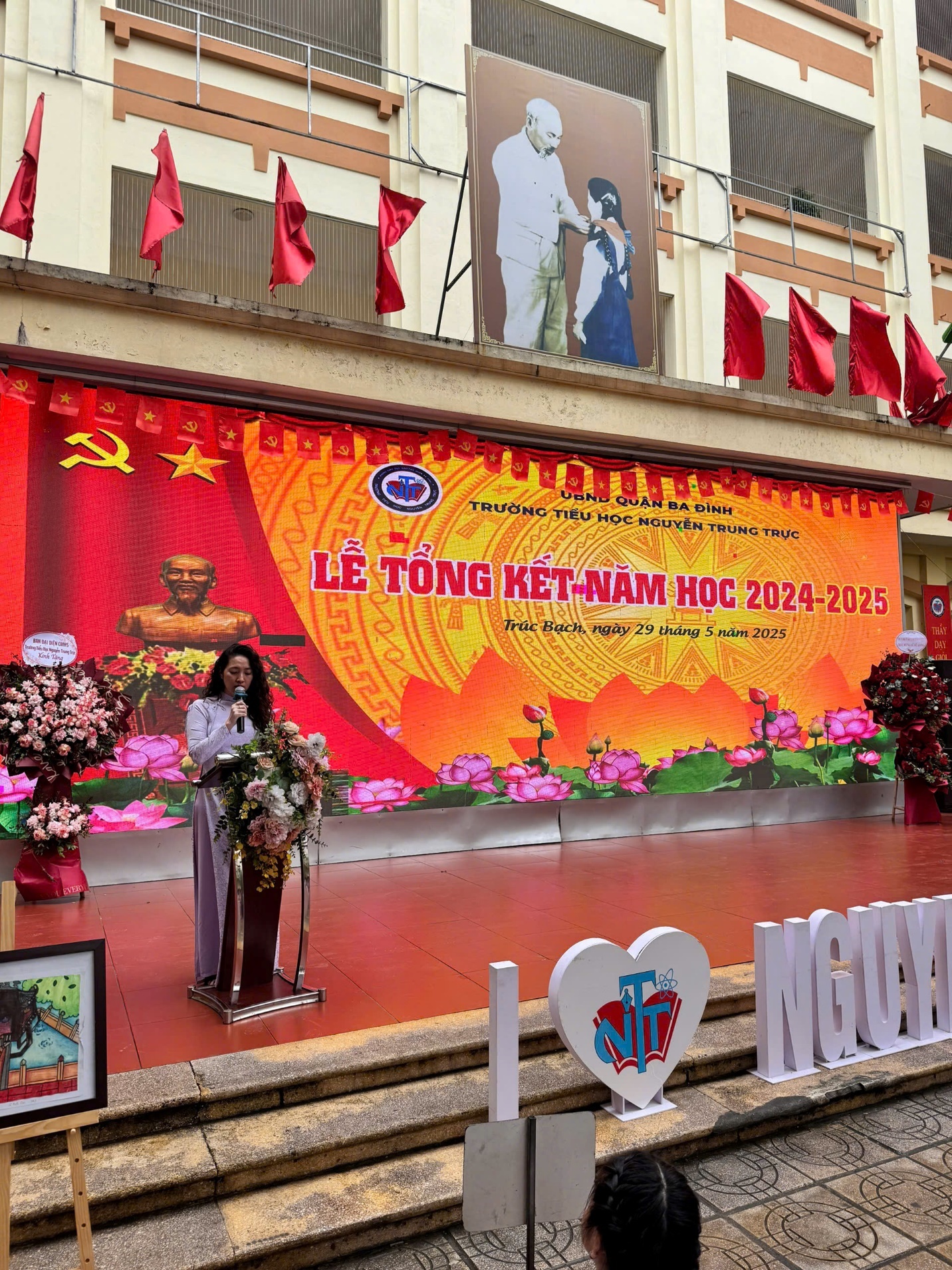 A person standing on stage with flowers and a banner

AI-generated content may be incorrect.