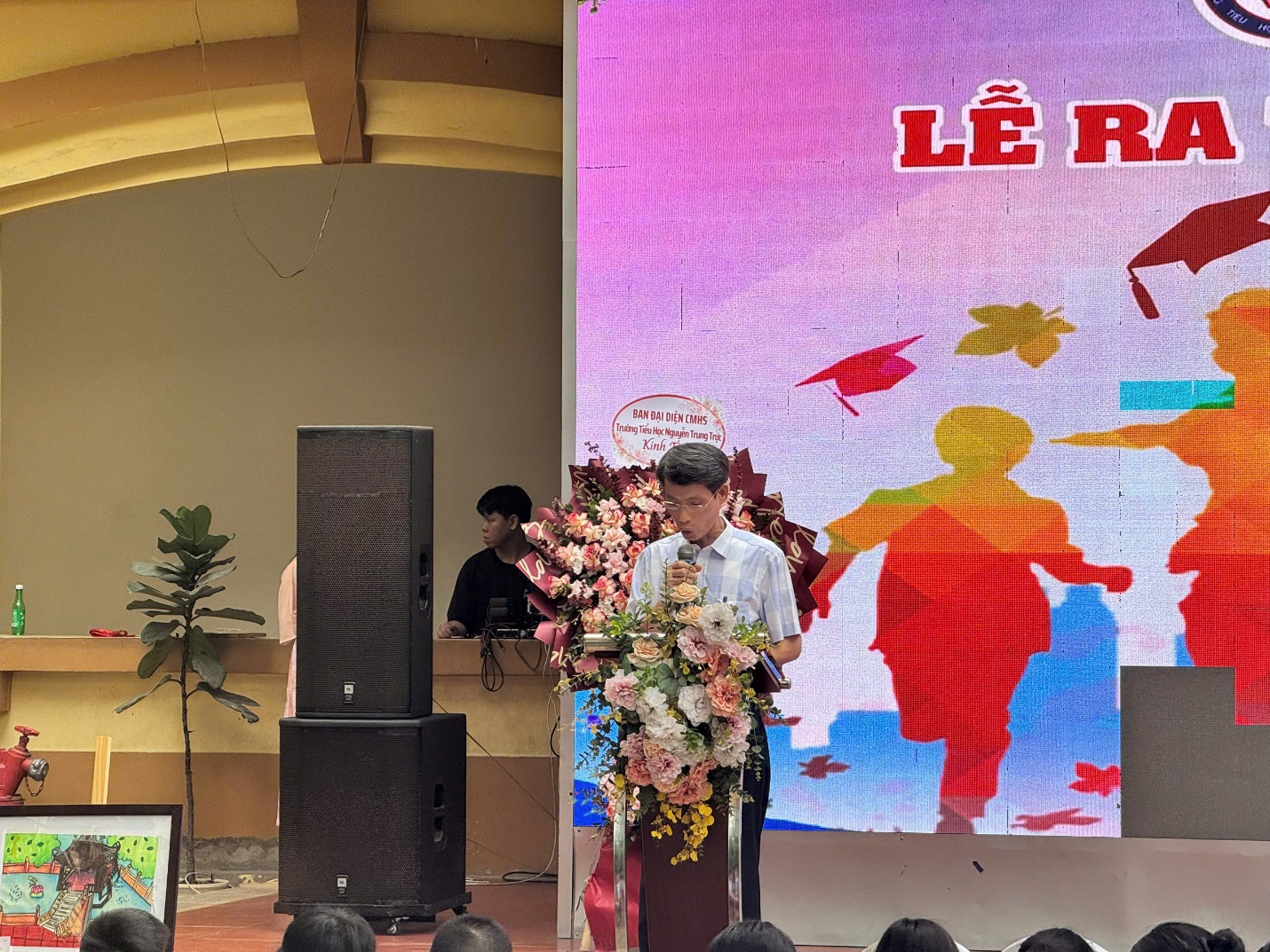 A person standing on a podium with flowers

AI-generated content may be incorrect.