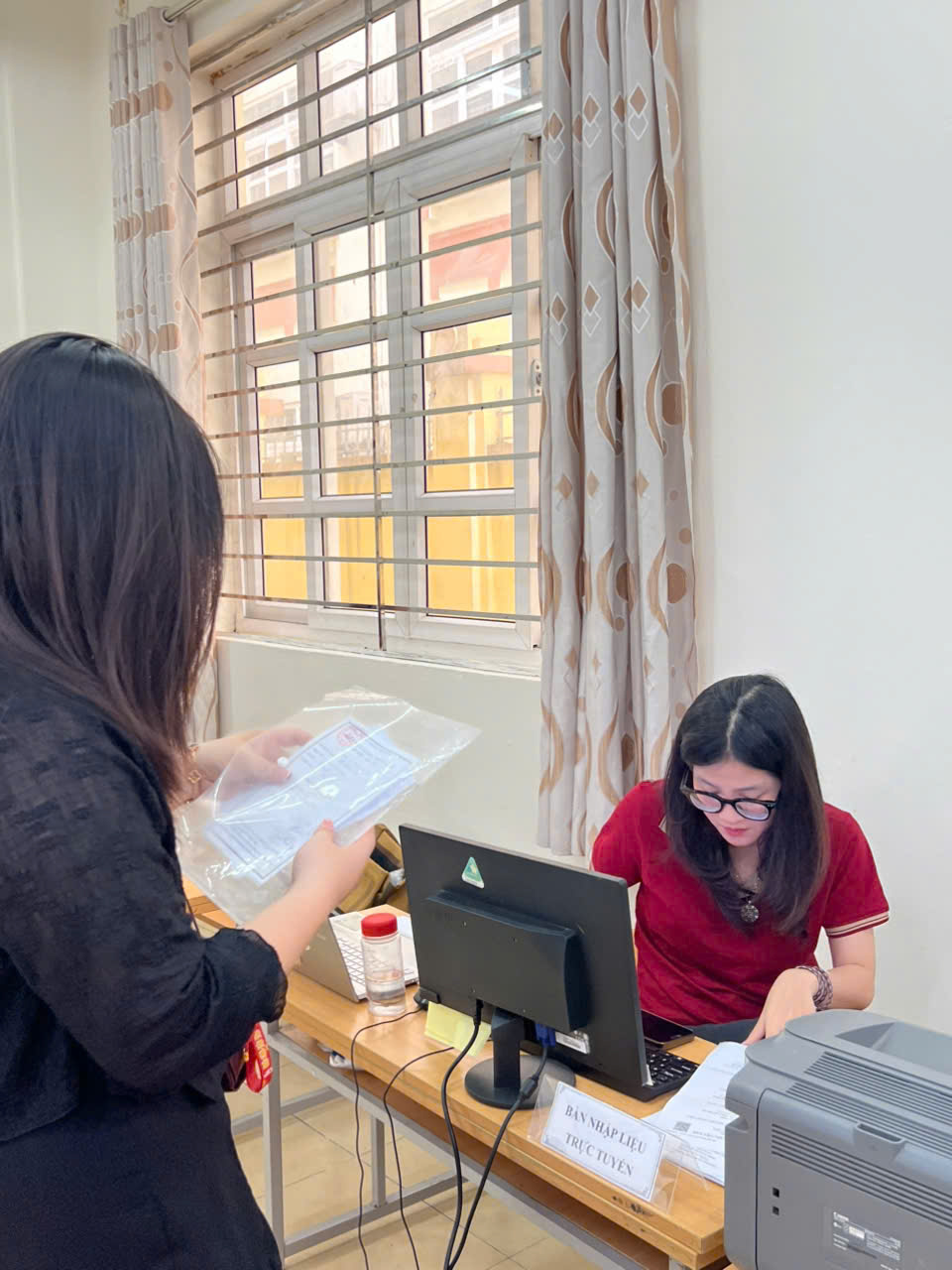 A person standing at a desk with a computer and a person holding a plastic bag

AI-generated content may be incorrect.
