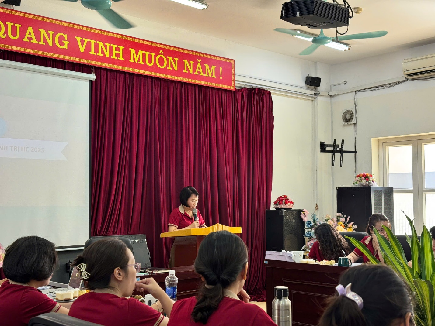 A person giving a presentation in a room with a red curtain

AI-generated content may be incorrect.