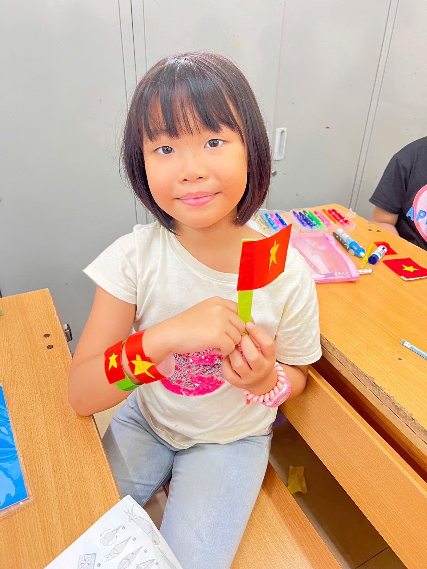 A child sitting at a desk holding a flag

AI-generated content may be incorrect.