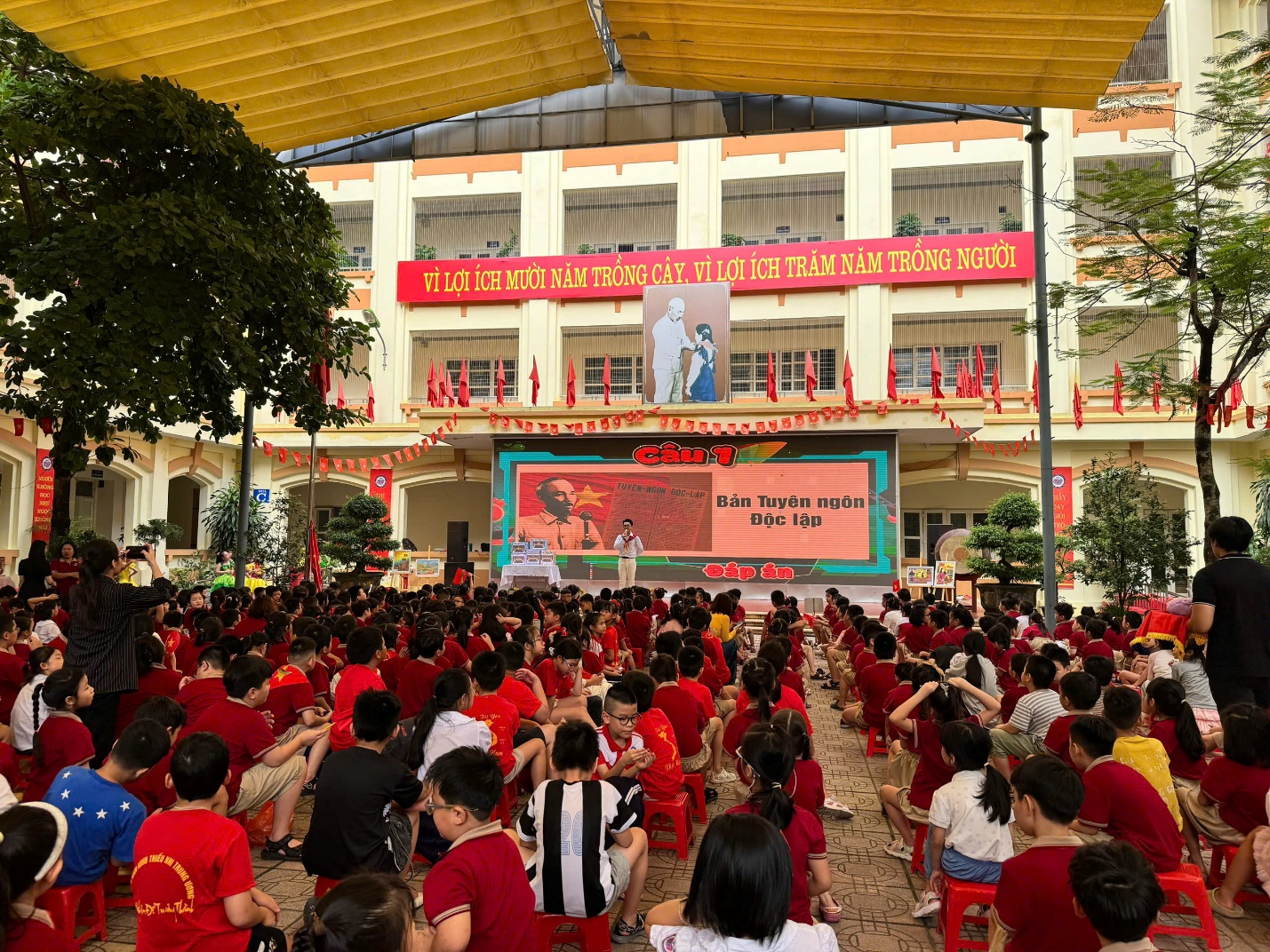 A group of people in red shirts sitting in front of a large building

AI-generated content may be incorrect.