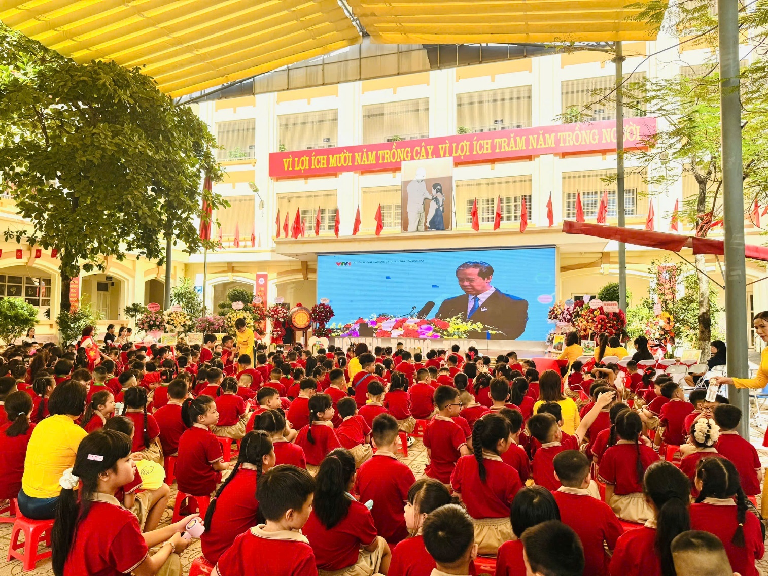 A group of children in red shirts sitting in a room with a large screen

AI-generated content may be incorrect.