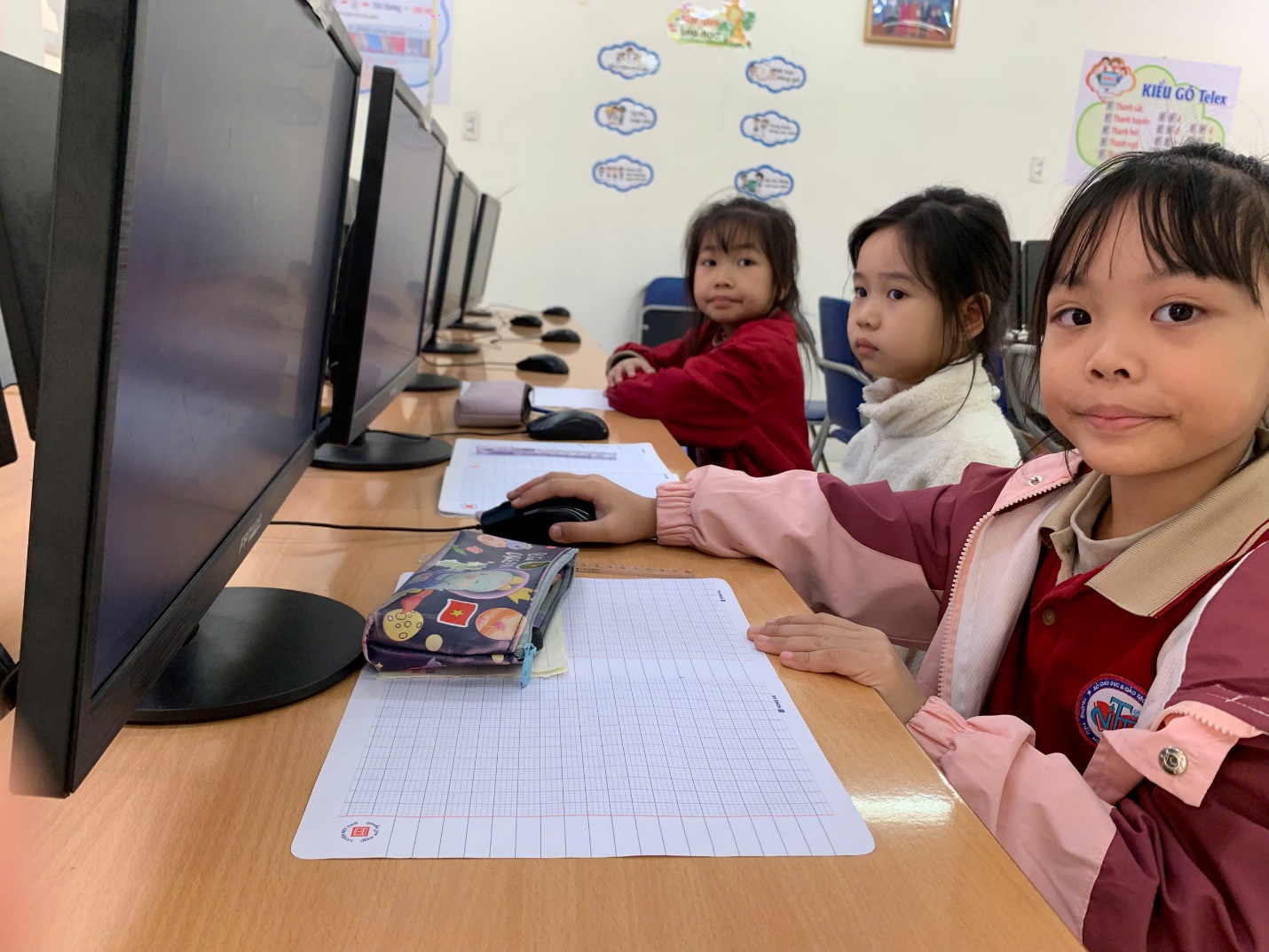 A group of children sitting at a desk with computers

AI-generated content may be incorrect.
