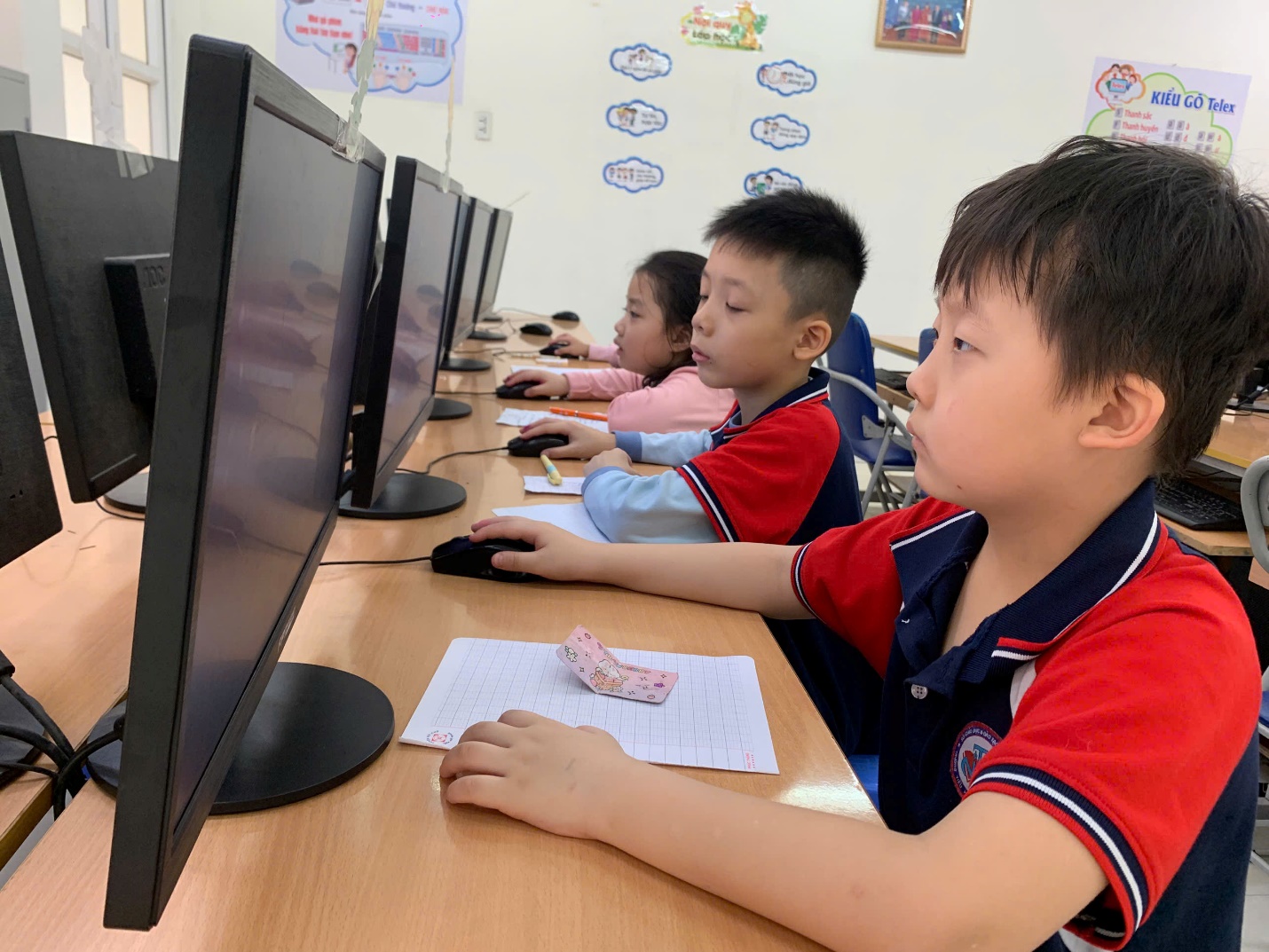 A group of children sitting at a desk using computers

AI-generated content may be incorrect.