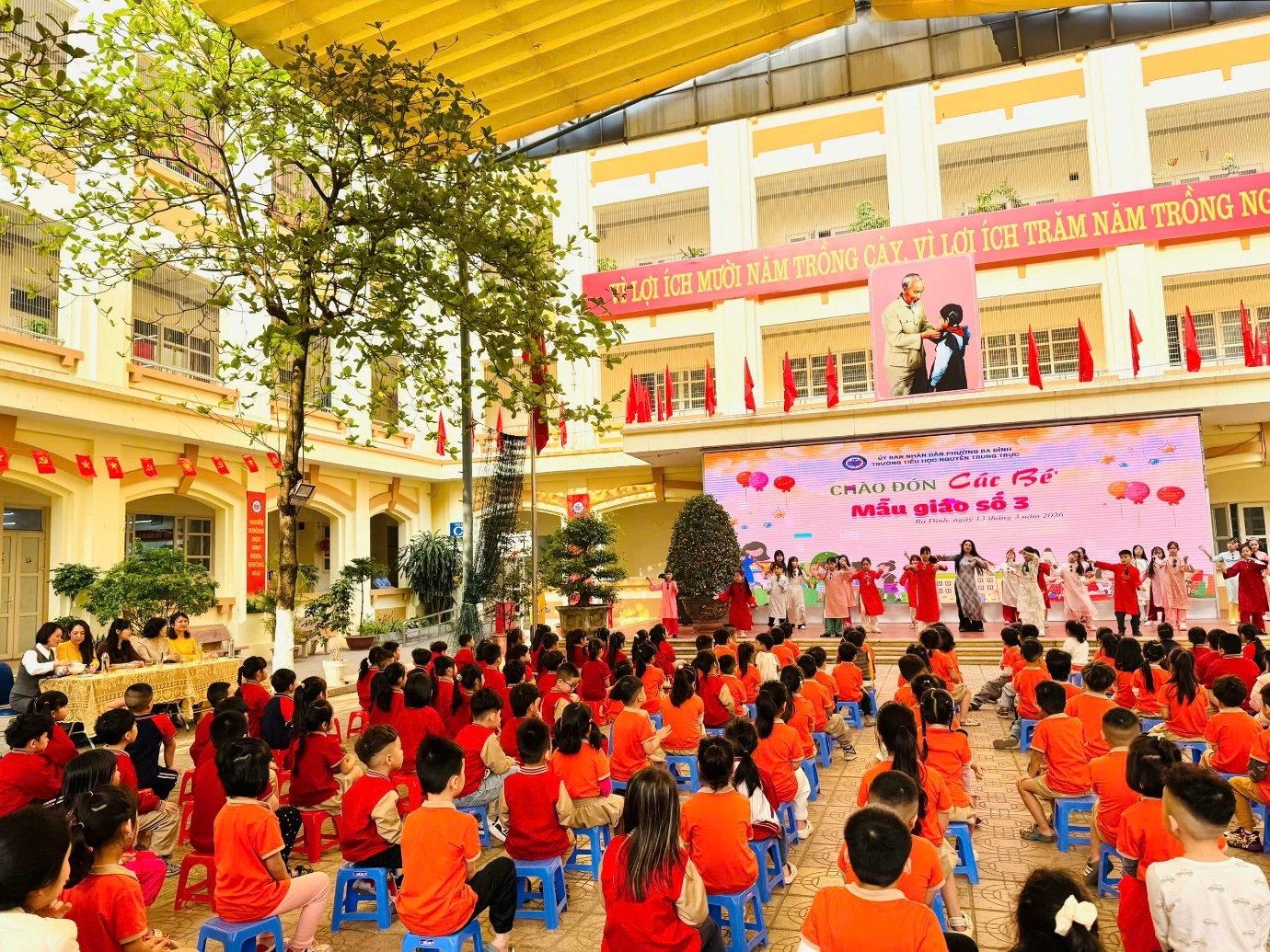 A group of children sitting on blue chairs in a courtyard

AI-generated content may be incorrect.
