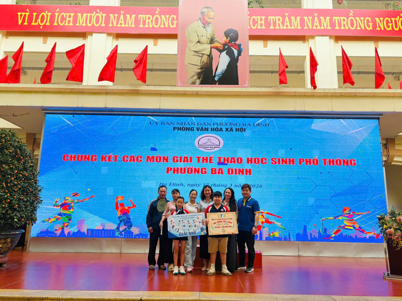 A group of people standing in front of a large blue sign
AI-generated content may be incorrect.